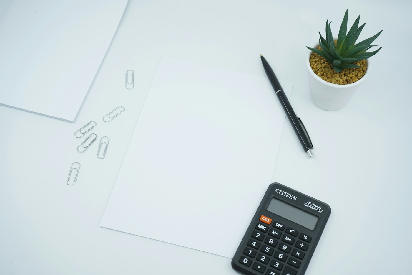 Calculator, pen and paper on a desk for reviewing the figures in an offer